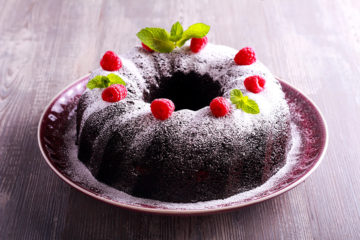chocolate cake topped with powdered sugar and raspberries